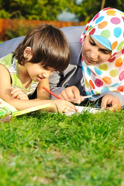 Mãe com filho, educação na natureza, colocando na grama com caderno — Fotografia de Stock