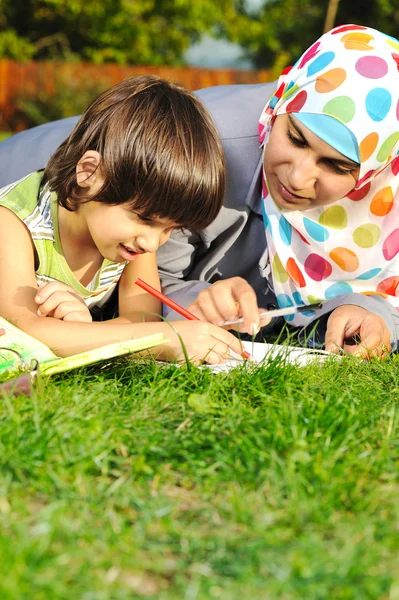 Madre con hijo, educación en la naturaleza, tendido sobre hierba con cuaderno —  Fotos de Stock