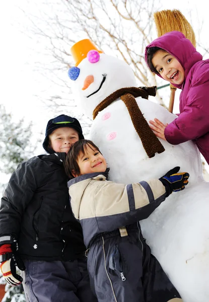 Niños y muñeco de nieve —  Fotos de Stock