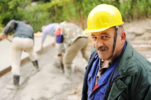 Äldre VD på arbetsplatsen med arbetstagare på färsk betong — Stockfoto