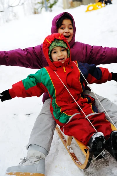 Dzieci bawić się razem przesuwne zjazd na dzień przyjemne zimą — Zdjęcie stockowe