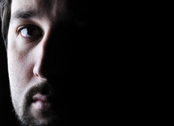 Low-key portrait - half face - sad and angry looking man — Stock Photo, Image