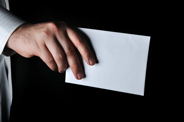 Hand hält einen weißen Umschlag mit dunklem Hintergrund — Stockfoto