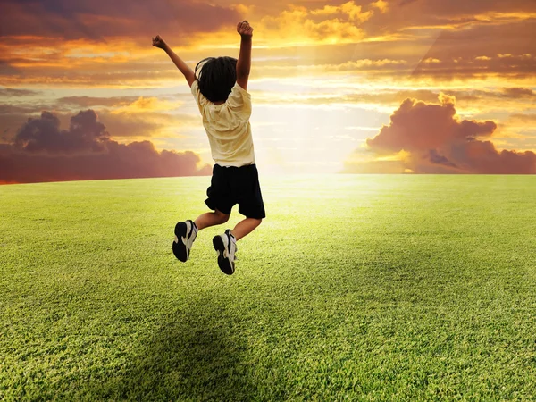Счастливый ребенок, прыгающий на зеленой горке — стоковое фото