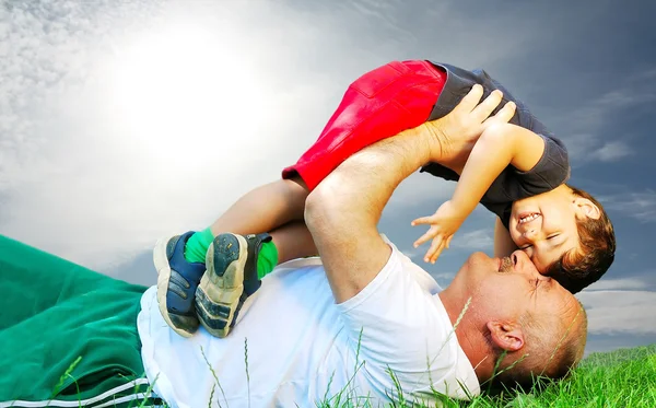 Un padre y su hijo tendidos y sonriendo en la hierba — Foto de Stock