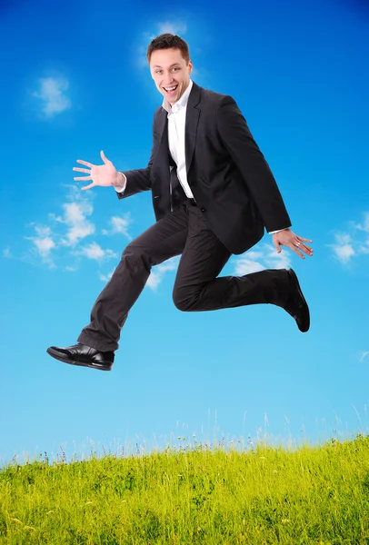 Jovem empresário pulando no prado verde — Fotografia de Stock