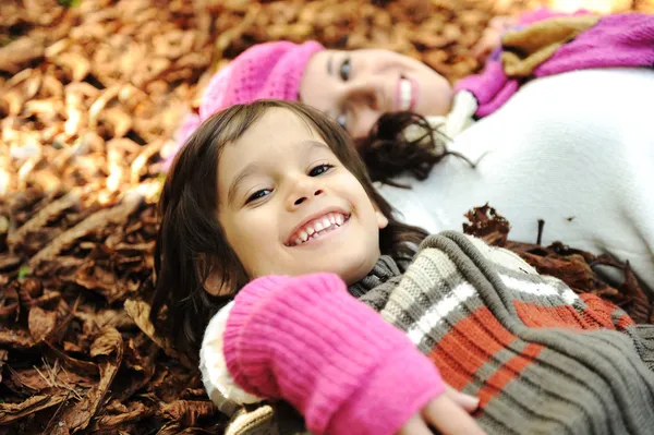 Retrato de cerca de una hermosa mujer y un niño de otoño tendidos en el suelo — Foto de Stock
