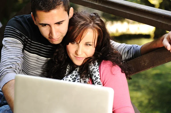 Pareja joven, hombre y mujer sentados en el parque y estudian y trabajan para conseguir —  Fotos de Stock