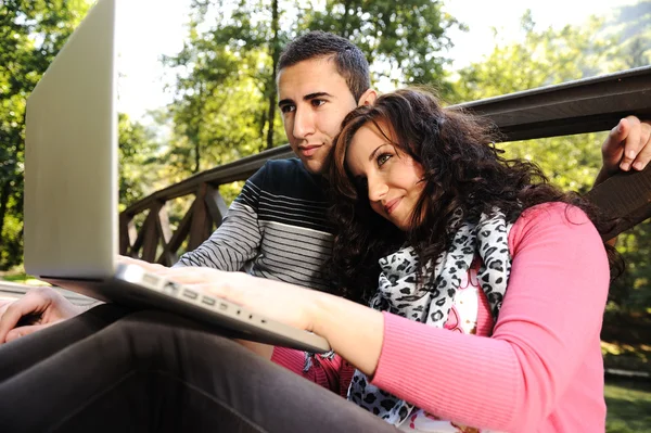 Молода пара, чоловік і жінка сидять в парку, навчаються і перемикаються — стокове фото