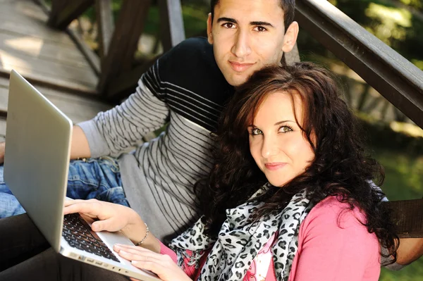 Pareja joven, hombre y mujer sentados en el parque y estudian y trabajan para conseguir — Foto de Stock