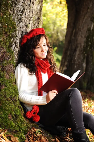 Beleza linda menina de outono sentado na natureza ao lado da árvore e lendo t — Fotografia de Stock