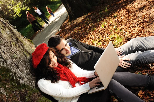 Mladý pár, samec a samice sedí v parku a studium a workind toget — Stock fotografie