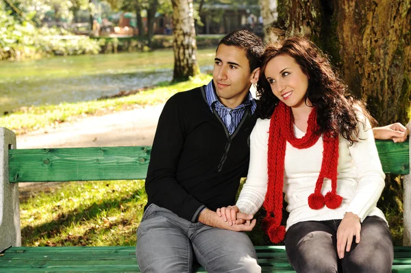若いカップルで自然のベンチに座って、男性と女性が一緒に — ストック写真