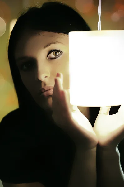 Young beautiful mysterious lady hiding behind the light in her hands with b — Stock Photo, Image