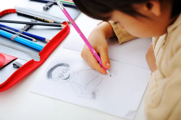 Schoolchild sta disegnando un uomo sul suo taccuino con una matita — Foto Stock