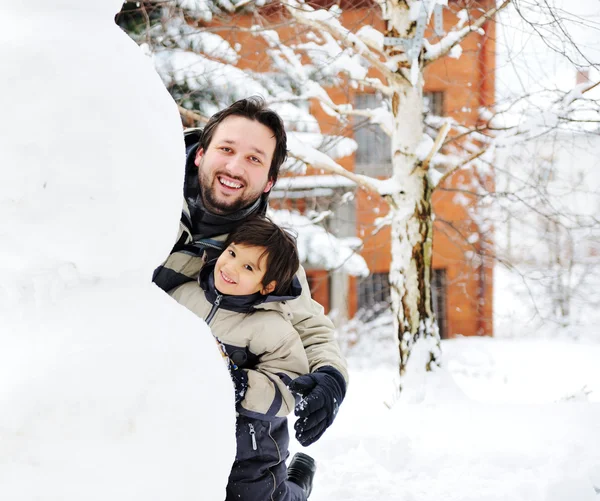 Padre e hijo jugando felizmente en nieve haciendo muñeco de nieve, temporada de invierno — Foto de Stock