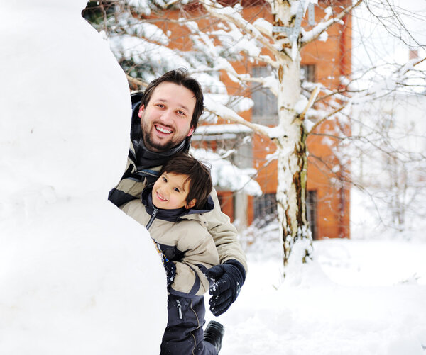 Отец и сын счастливо играют в снегопад снеговик, зимний сезон
