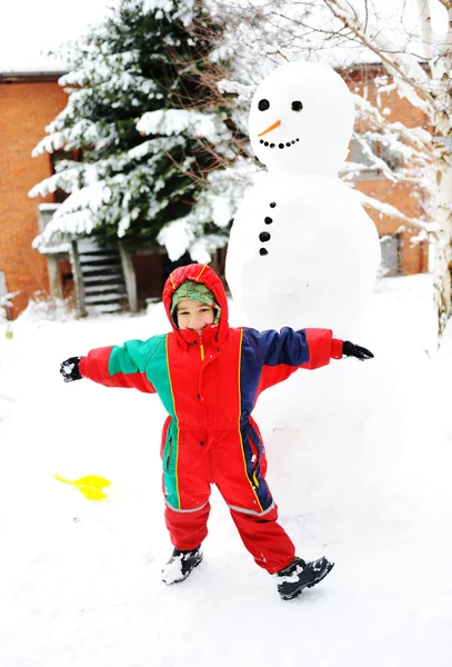 Ребенок счастливо играет в снегопад снеговик, зимний сезон — стоковое фото