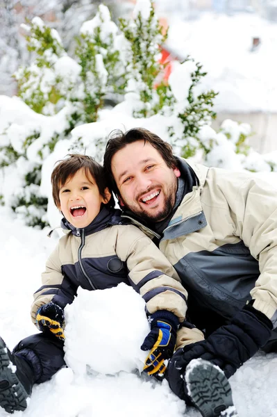 Padre e hijo jugando felizmente en nieve haciendo muñeco de nieve, temporada de invierno — Foto de Stock
