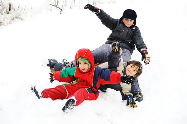 Grupo de niños jugando felizmente en nieve, invierno — Foto de Stock