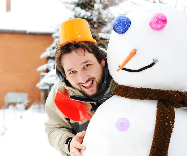 Winter snowman, snow show and happy funny young man who made him