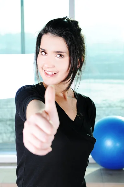 Fitness sporty girl excercising with a ball and showing a thumb up with sm — Stock Photo, Image