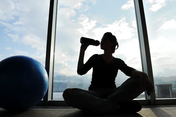Fitness menina desportiva silhueta excercising e beber uma água — Fotografia de Stock