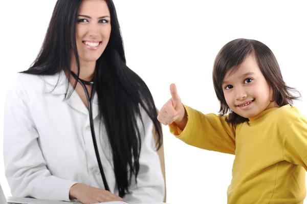 Junge Ärztin untersucht kleines süßes glückliches Kind mit erhobenem Daumen, gut Stockfoto