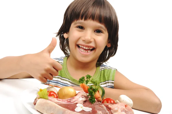 Ładny chłopiec pozytywne i surowe mięso i warzywa w płycie czytanie do gotowania Zdjęcia Stockowe bez tantiem