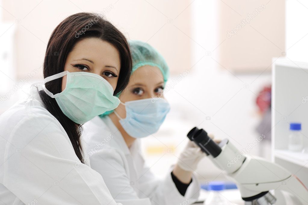 Two scientists working at the laboratory with microscope