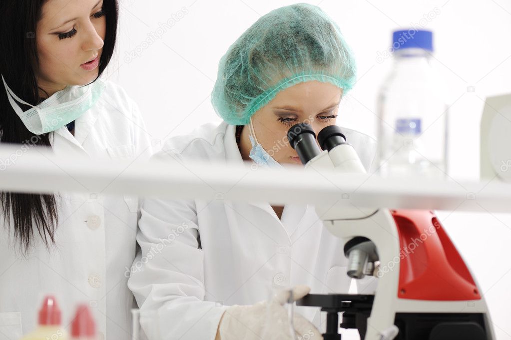 Two female scientists working at the laboratory with microscope