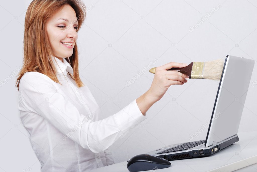 Young lady erasing and painting laptop with brush in hand