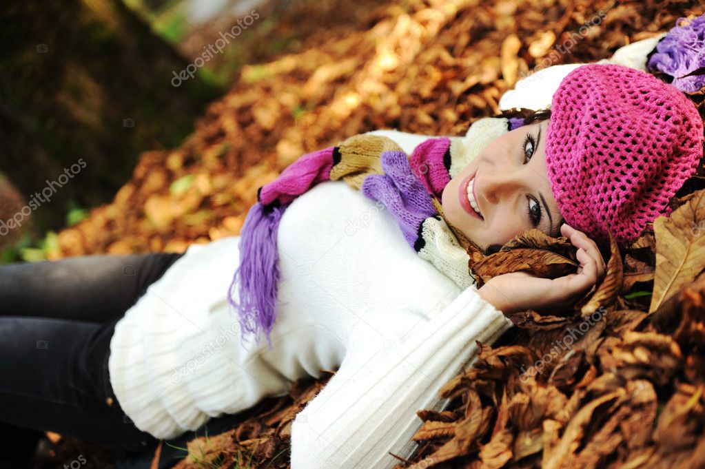 Young beauty girl laying on autumn ground and leaves, perfect face and natu