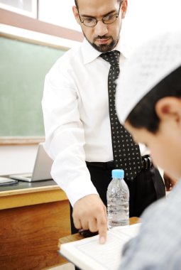 Young teacher helping a student in classroom clipart