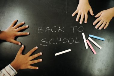 Multiraces children hands on blackboard with chalks: back to school! clipart