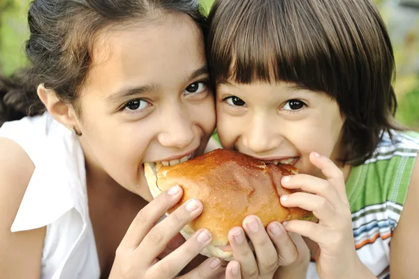 Nahaufnahme von zwei Kindern, die gemeinsam in der Natur Sandwich essen, gesunde Ernährung, — Stockfoto