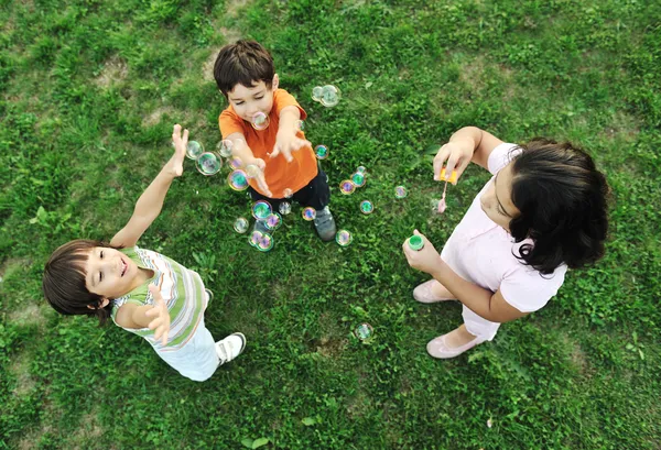 Μικρή ομάδα ευτυχισμένα παιδιά κάνοντας φυσαλίδες και να παίζουν μαζί στη φύση — Φωτογραφία Αρχείου