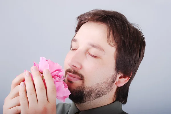 Симпатичный мужчина, нюхающий розовые розы — стоковое фото