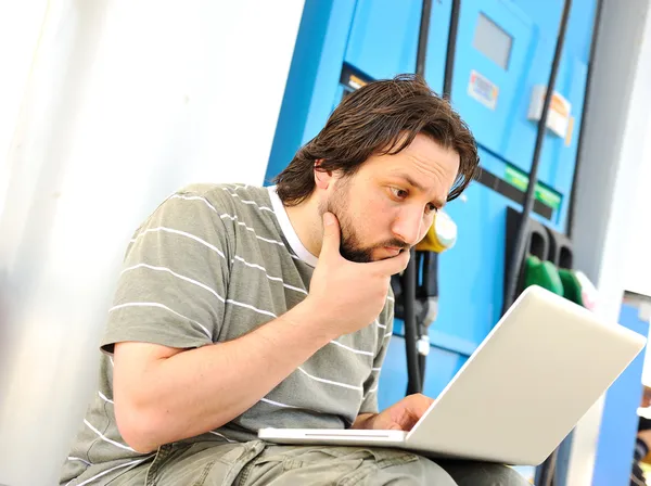 Hombre con portátil en la gasolinera con expresión tonta en la cara después de leer —  Fotos de Stock