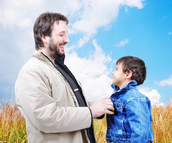 Молодой отец помогает сыну с осенью - зимняя одежда на открытом воздухе, счастливый пейзаж — стоковое фото