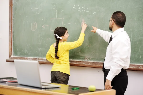 Učitelka pomáhá školačka přední deska — Stock fotografie