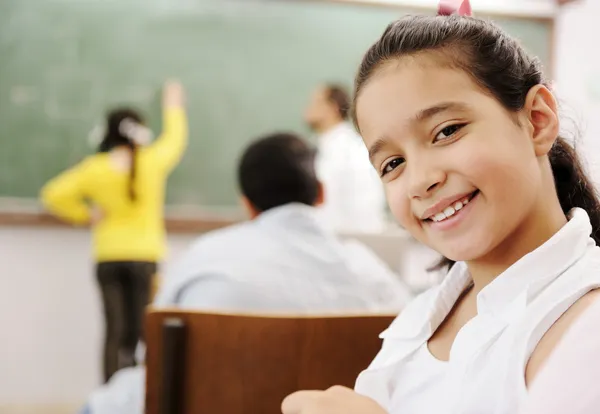 Bedårande flicka leende i skolan klassrum och bakom hennes klass aktiviteter — Stockfoto