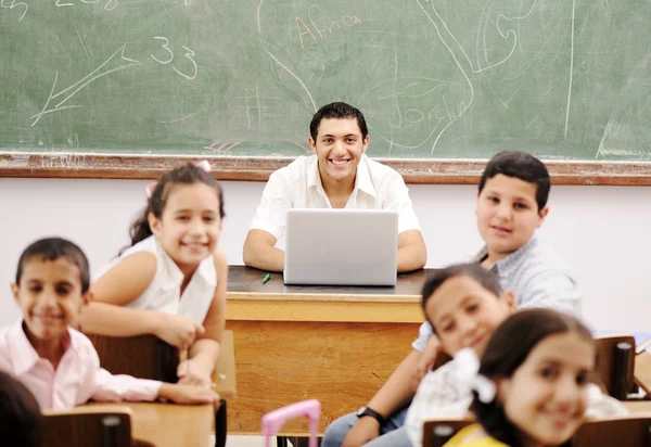 Szczęśliwy młody nauczyciel i dzieci w klasie razem — Zdjęcie stockowe