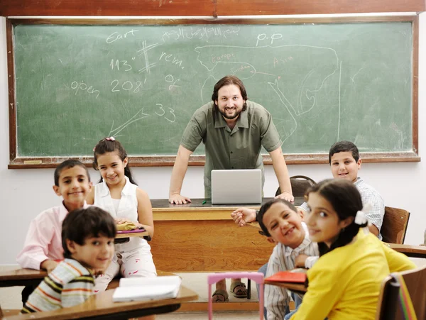 Lehrer im Klassenzimmer mit seinen kleinen glücklichen Schülern — Stockfoto
