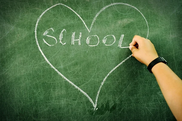 Child drawing and writing on board: heart and school — Stock Photo, Image