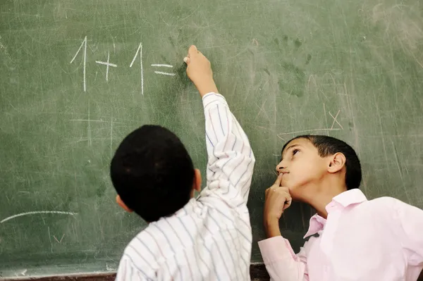 Two boys in classroom thinking, writing and counting on board — Stock Photo, Image