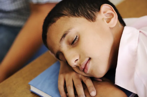 Kid in classroom on desk falling asleep on his notebook — Stock Photo, Image