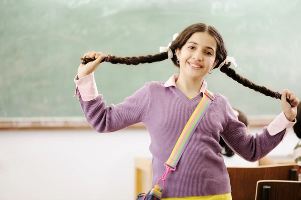Wunderschönes Mädchen, das ihre Haare hält und im Klassenzimmer vor der Tafel steht — Stockfoto