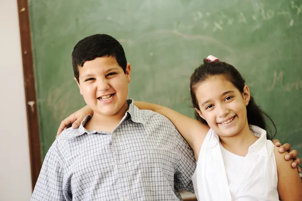 Two happy friends in front of green classroom board, school activities — Stock Photo, Image