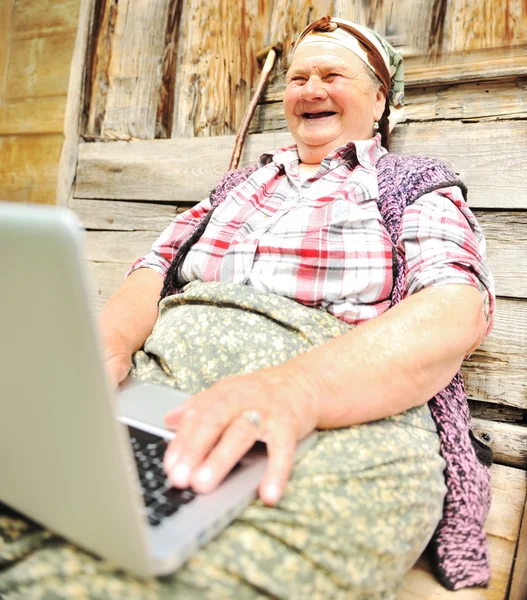 Όλο το μήκος της ανώτερος γυναίκα κάθεται και χρησιμοποιώντας ένα φορητό υπολογιστή κατά — Φωτογραφία Αρχείου